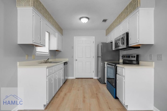 kitchen featuring a sink, white cabinetry, stainless steel appliances, and light countertops