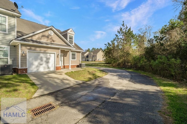 view of front of home with concrete driveway, an attached garage, and central AC