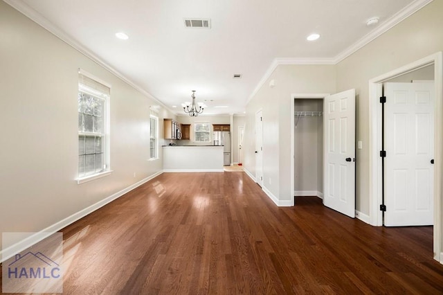 unfurnished living room with visible vents, dark wood-type flooring, baseboards, ornamental molding, and an inviting chandelier