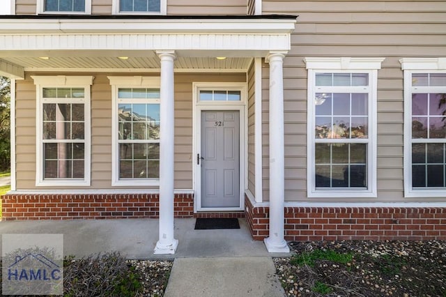 doorway to property with brick siding and a porch