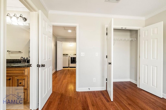 interior space featuring a sink, wood finished floors, crown molding, and separate washer and dryer