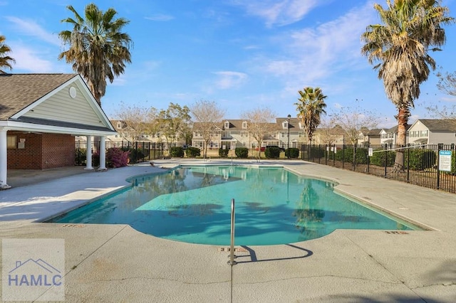 pool with a patio area, a residential view, and fence