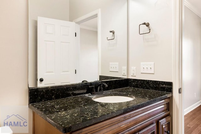 bathroom with ornamental molding, vanity, baseboards, and wood finished floors