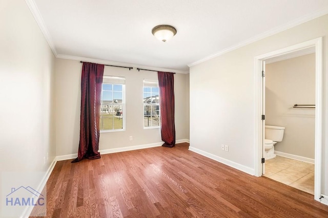 spare room featuring wood finished floors, baseboards, and ornamental molding