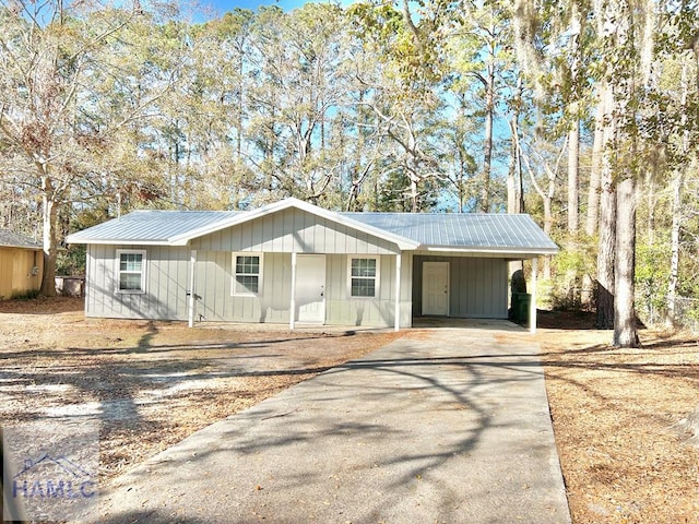 ranch-style house featuring an attached carport, driveway, and metal roof