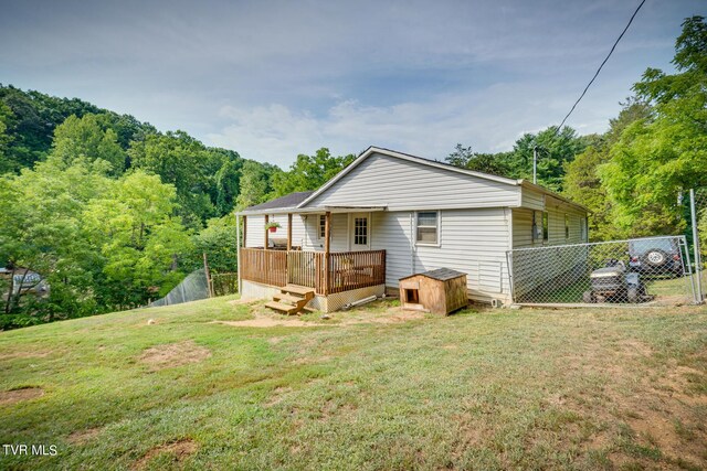 rear view of house with a porch, a lawn, and fence