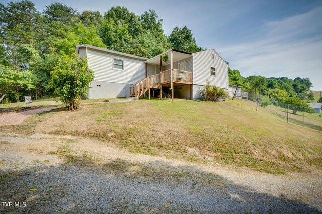 view of front facade with a wooden deck and a front lawn