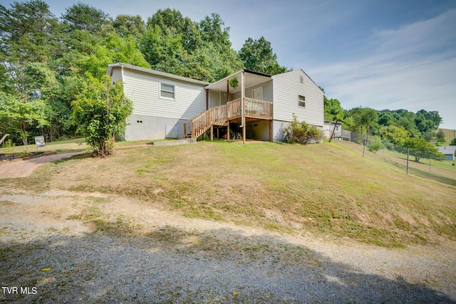 rear view of house featuring a deck, a lawn, stairway, and fence