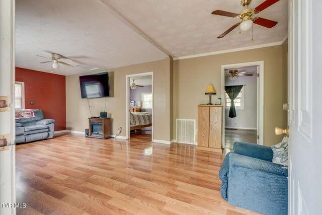 living room featuring hardwood / wood-style flooring, ornamental molding, and ceiling fan