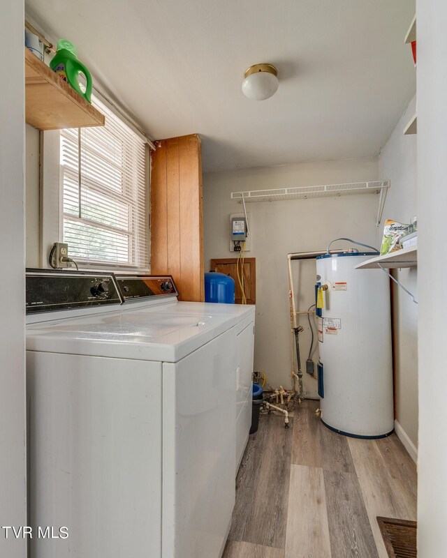 laundry room featuring water heater, laundry area, light wood-style floors, and washer and dryer