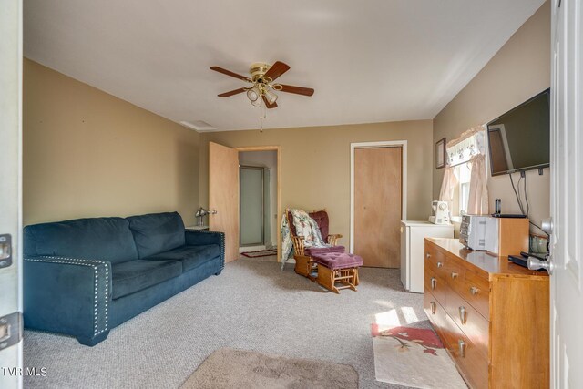 carpeted living room with ceiling fan and independent washer and dryer