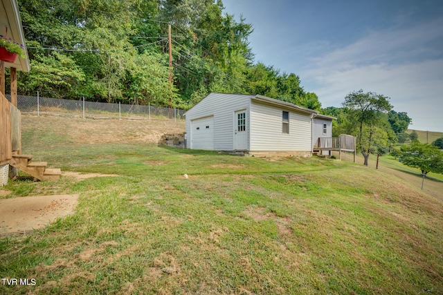 view of yard with a garage, an outbuilding, and a deck