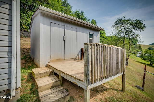 wooden deck featuring a storage shed and a lawn