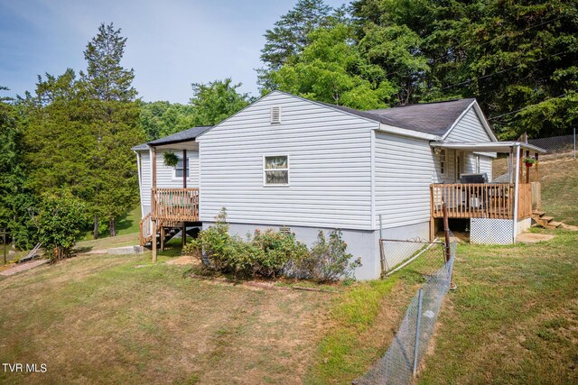 view of side of home with a wooden deck, fence, and a yard