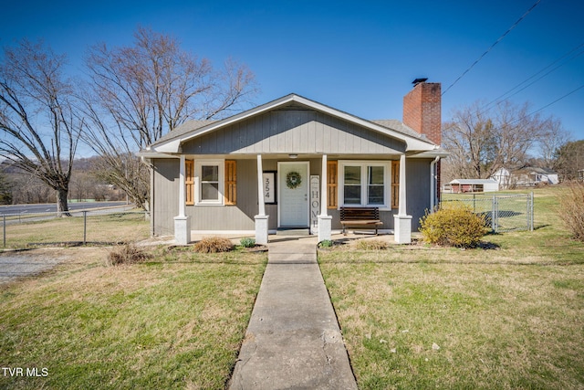 bungalow-style house featuring a porch, fence, a chimney, and a front lawn