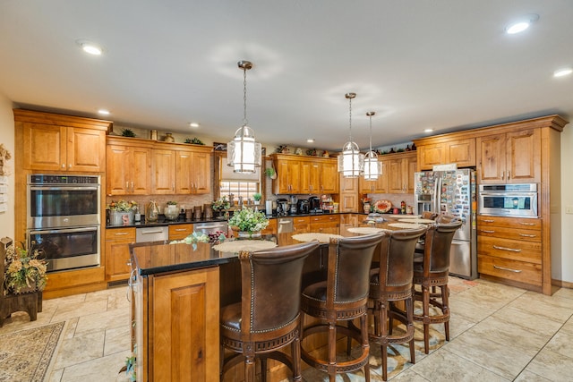 kitchen featuring a kitchen island, hanging light fixtures, light tile flooring, and appliances with stainless steel finishes