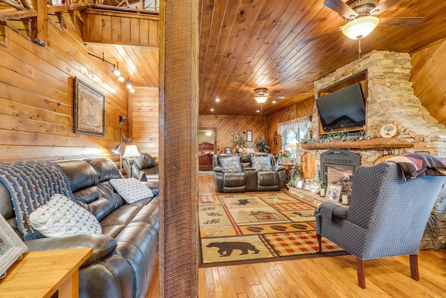 living room featuring ceiling fan, wooden ceiling, wood walls, and light wood-type flooring