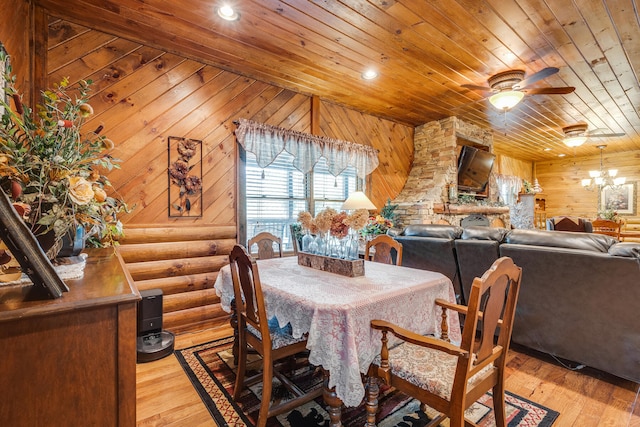 dining space with wood walls, ceiling fan with notable chandelier, wooden ceiling, and light wood-type flooring