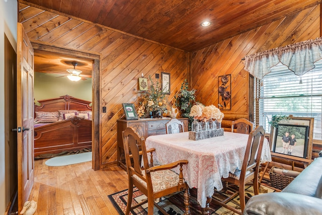 dining space with ceiling fan, light hardwood / wood-style floors, wooden ceiling, wood walls, and vaulted ceiling