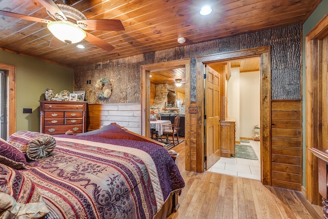 bedroom with wooden ceiling, ceiling fan, wood walls, and light hardwood / wood-style flooring