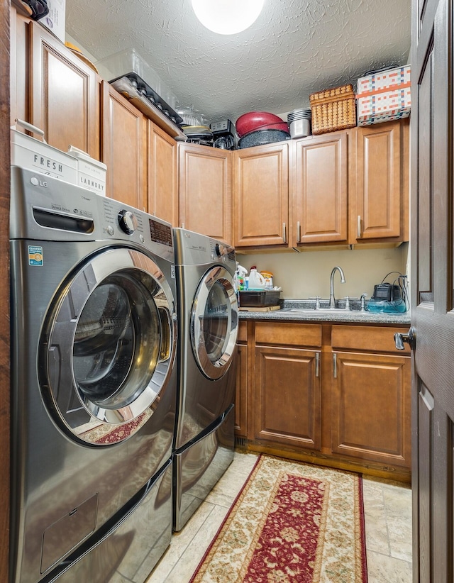 laundry room featuring light tile flooring, a textured ceiling, sink, cabinets, and separate washer and dryer