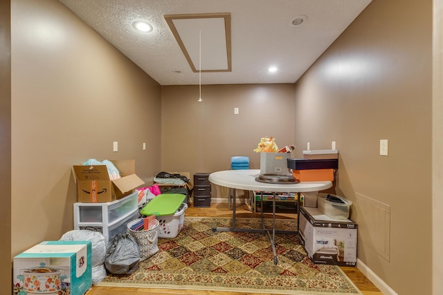 recreation room with a textured ceiling and wood-type flooring