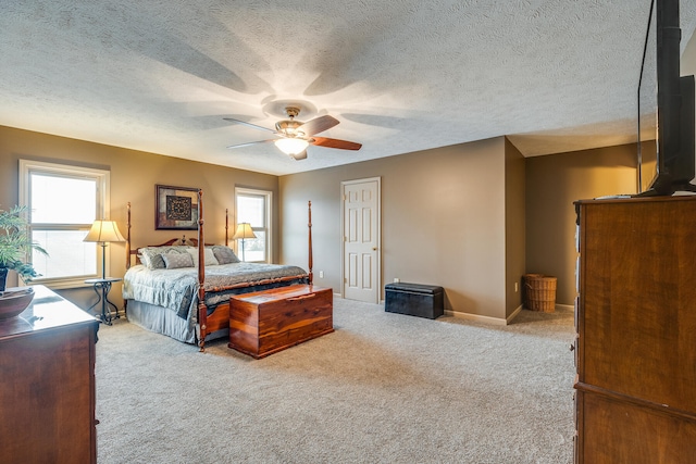 bedroom featuring light colored carpet, ceiling fan, and a textured ceiling