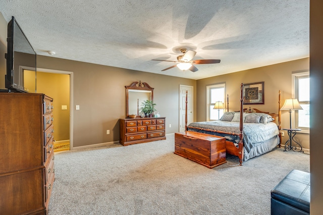 bedroom featuring ceiling fan, a textured ceiling, light carpet, and multiple windows