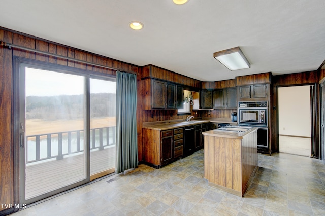 kitchen featuring light tile flooring, a center island with sink, dark brown cabinets, oven, and dishwasher