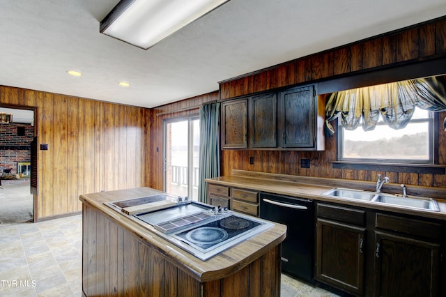 kitchen featuring a fireplace, sink, light tile floors, wood walls, and dishwasher