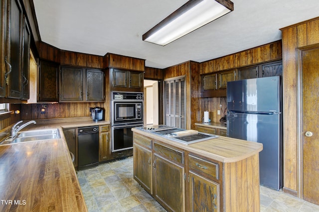 kitchen with wood counters, a center island, black appliances, sink, and light tile flooring