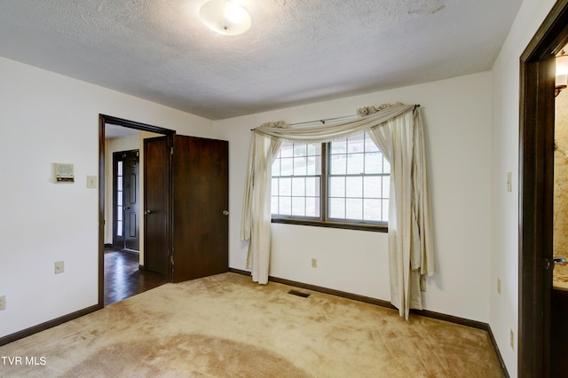 carpeted spare room with a textured ceiling