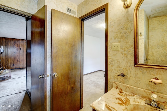 bathroom featuring wooden walls, a textured ceiling, and sink