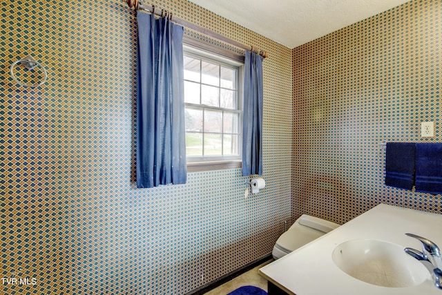 bathroom with a textured ceiling, tile walls, toilet, and vanity