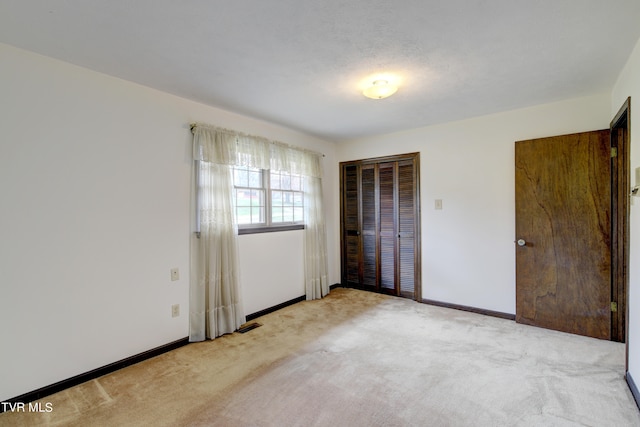 unfurnished bedroom featuring a closet and light carpet