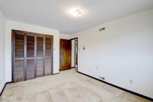 unfurnished bedroom with a closet and light colored carpet