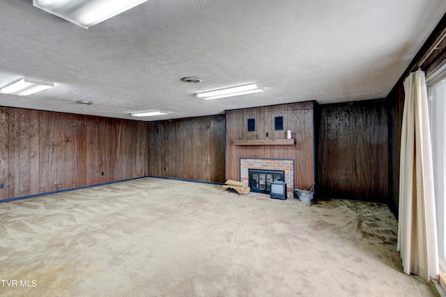 basement featuring wooden walls, light carpet, a fireplace, and a textured ceiling