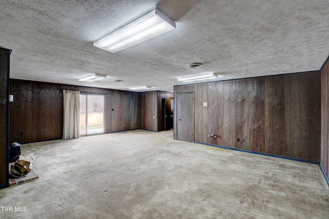 basement featuring wood walls, a textured ceiling, and light carpet