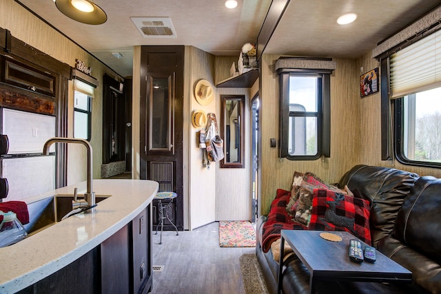 interior space with wooden walls, light stone countertops, dark brown cabinets, and dark hardwood / wood-style floors