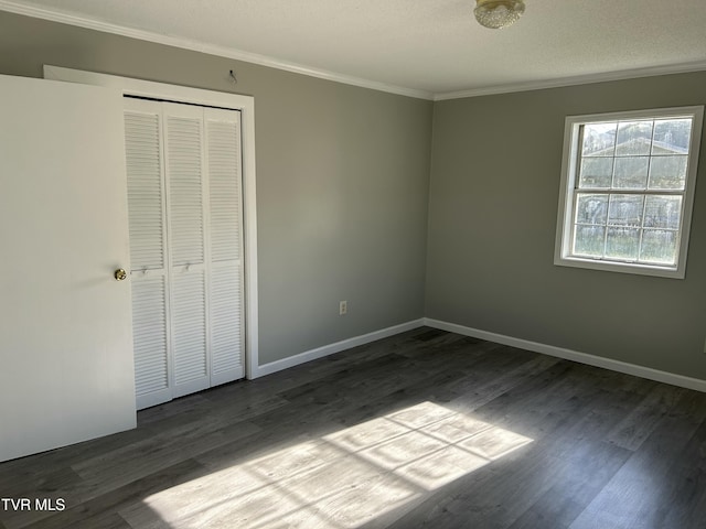 unfurnished bedroom with ornamental molding, a textured ceiling, dark hardwood / wood-style flooring, and a closet