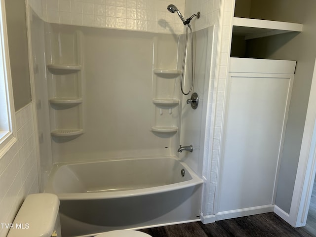 bathroom featuring shower / tub combination, wood-type flooring, toilet, and tile walls