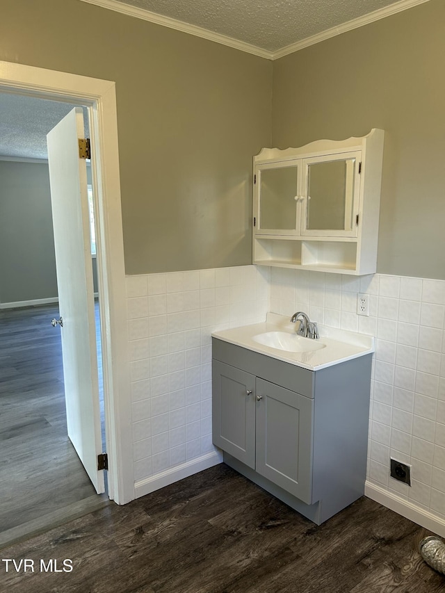 bathroom with wood-type flooring, a textured ceiling, tile walls, ornamental molding, and vanity