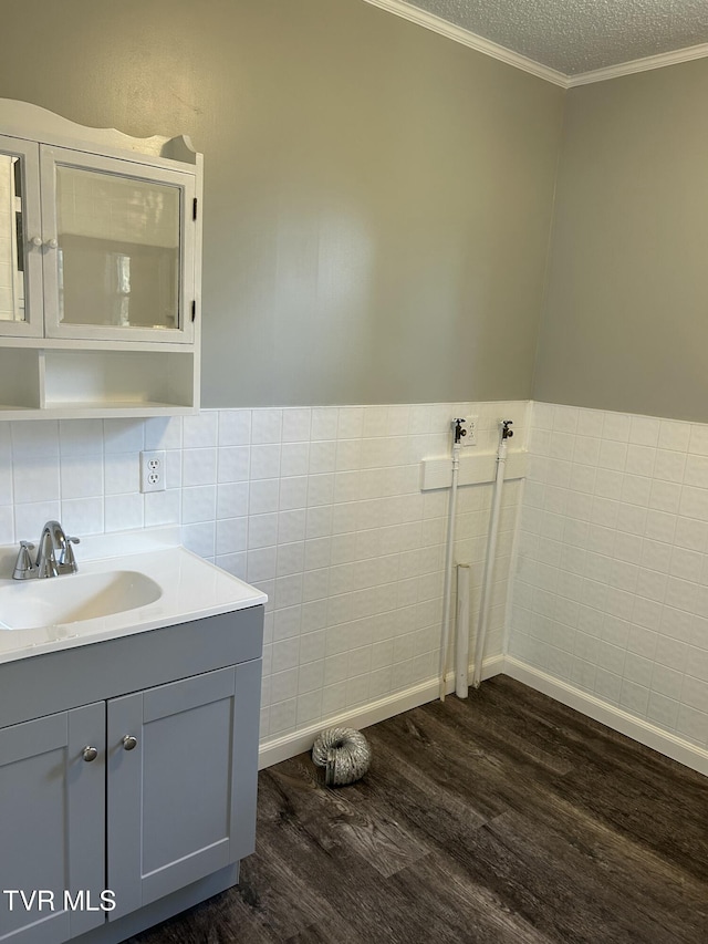 bathroom with tile walls, hardwood / wood-style flooring, ornamental molding, and a textured ceiling