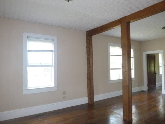 unfurnished room featuring dark hardwood / wood-style flooring and a wealth of natural light