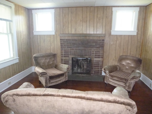 living room with dark hardwood / wood-style floors, a fireplace, and wood walls