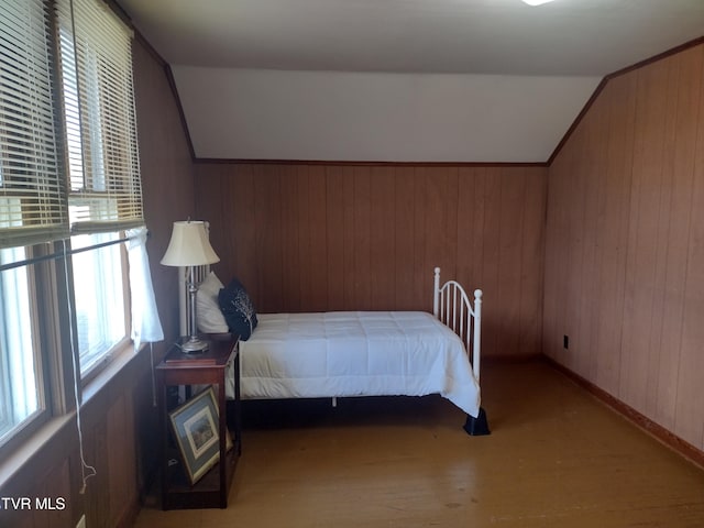 bedroom featuring lofted ceiling, wooden walls, and hardwood / wood-style flooring