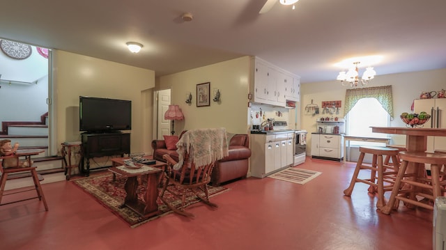 living room featuring concrete flooring and ceiling fan with notable chandelier