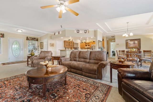 living room with light colored carpet, ornamental molding, a tray ceiling, and ceiling fan with notable chandelier