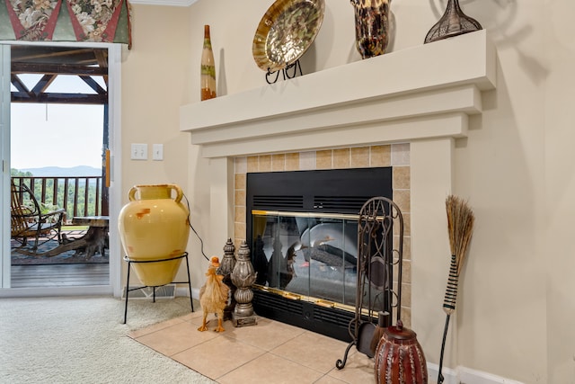 interior details featuring a tiled fireplace and light carpet