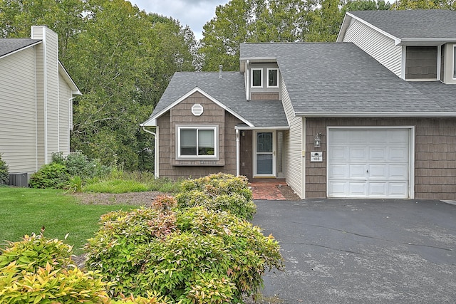 view of front facade with a garage, a front yard, and cooling unit